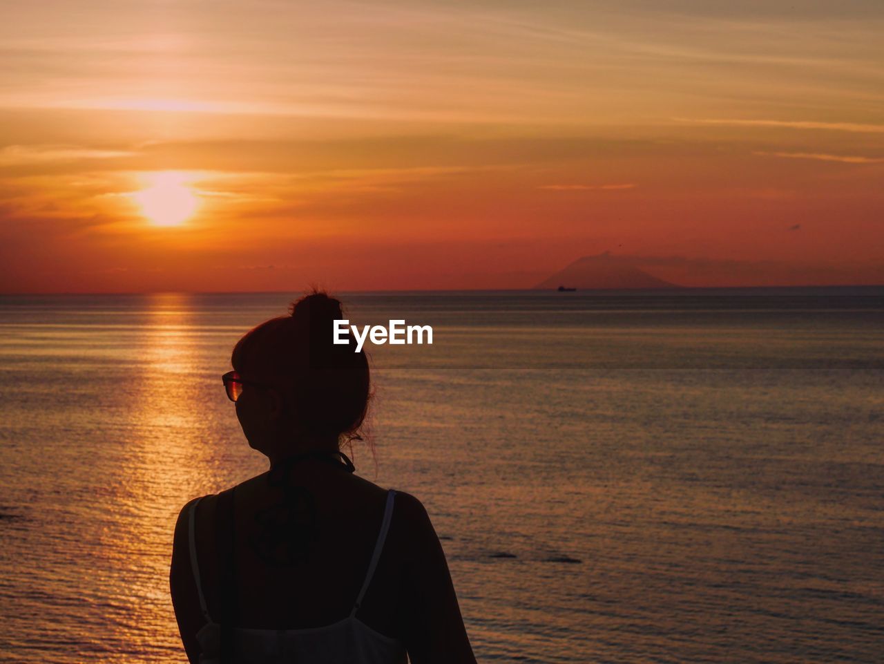 Rear view of woman against sea and sky during sunset