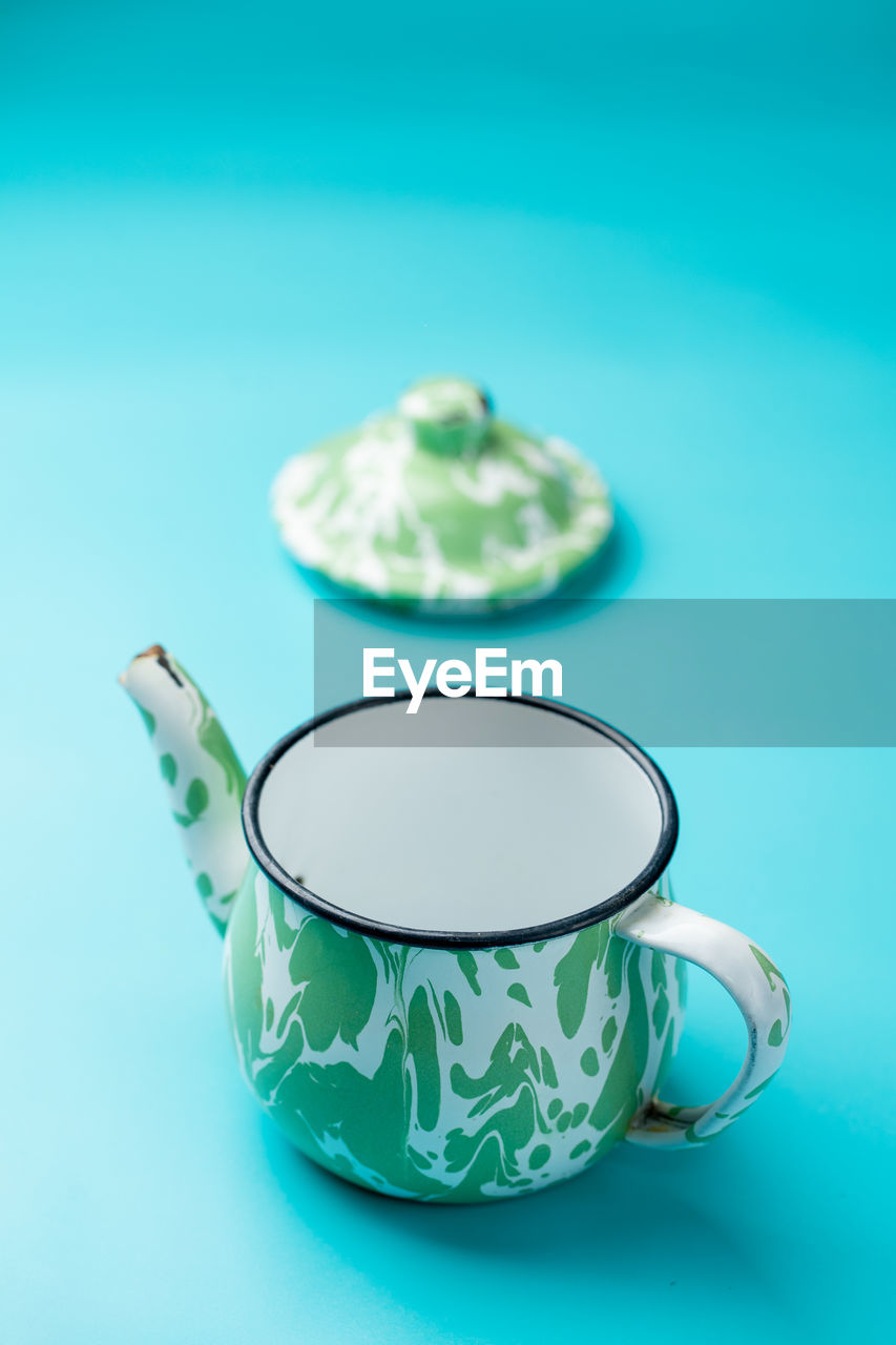 An enamel teapot on light blue background
