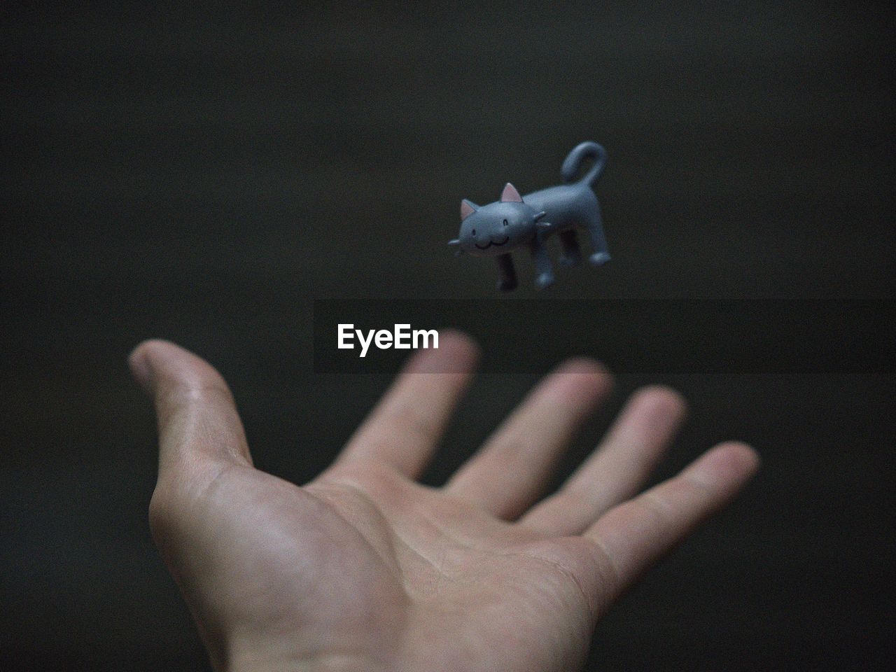 Cropped hand of man reaching toy against wall