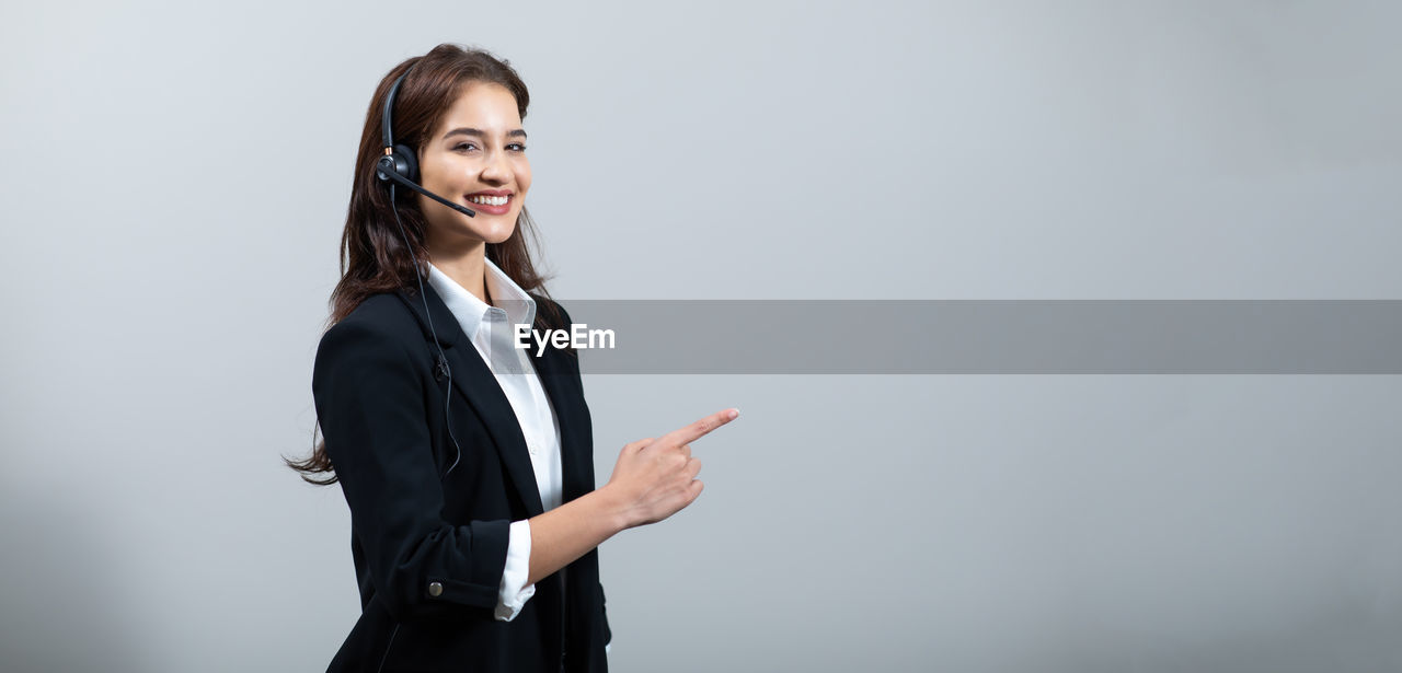 PORTRAIT OF A SMILING YOUNG WOMAN STANDING ON WALL AT HOME