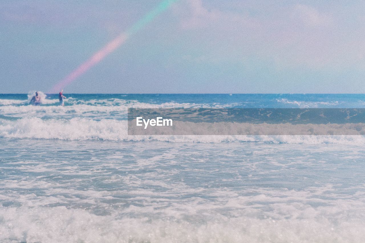 SCENIC VIEW OF SEA AGAINST VAPOR TRAILS IN SKY