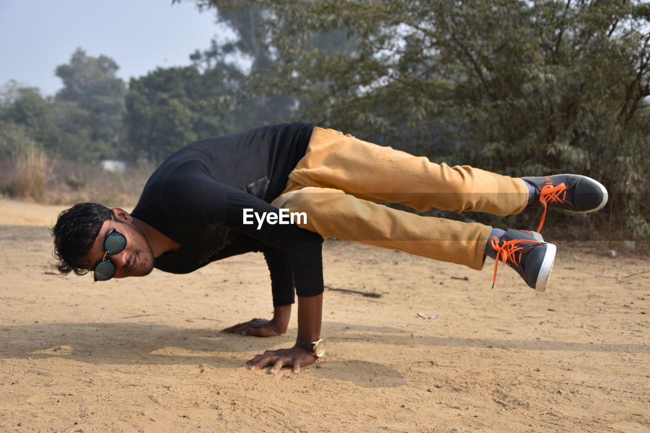 Portrait of man wearing sunglasses performing handstand outdoors