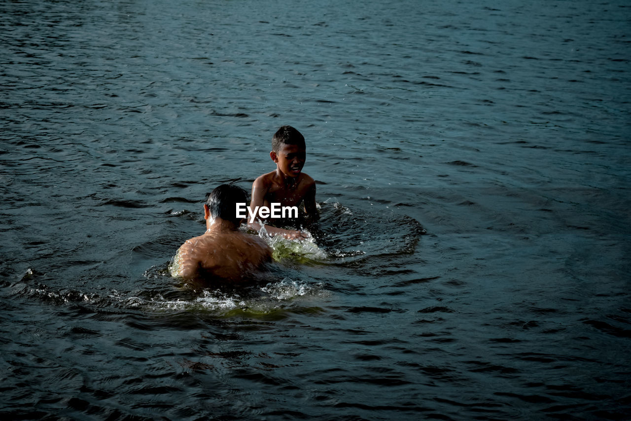 Full length of shirtless man swimming in sea
