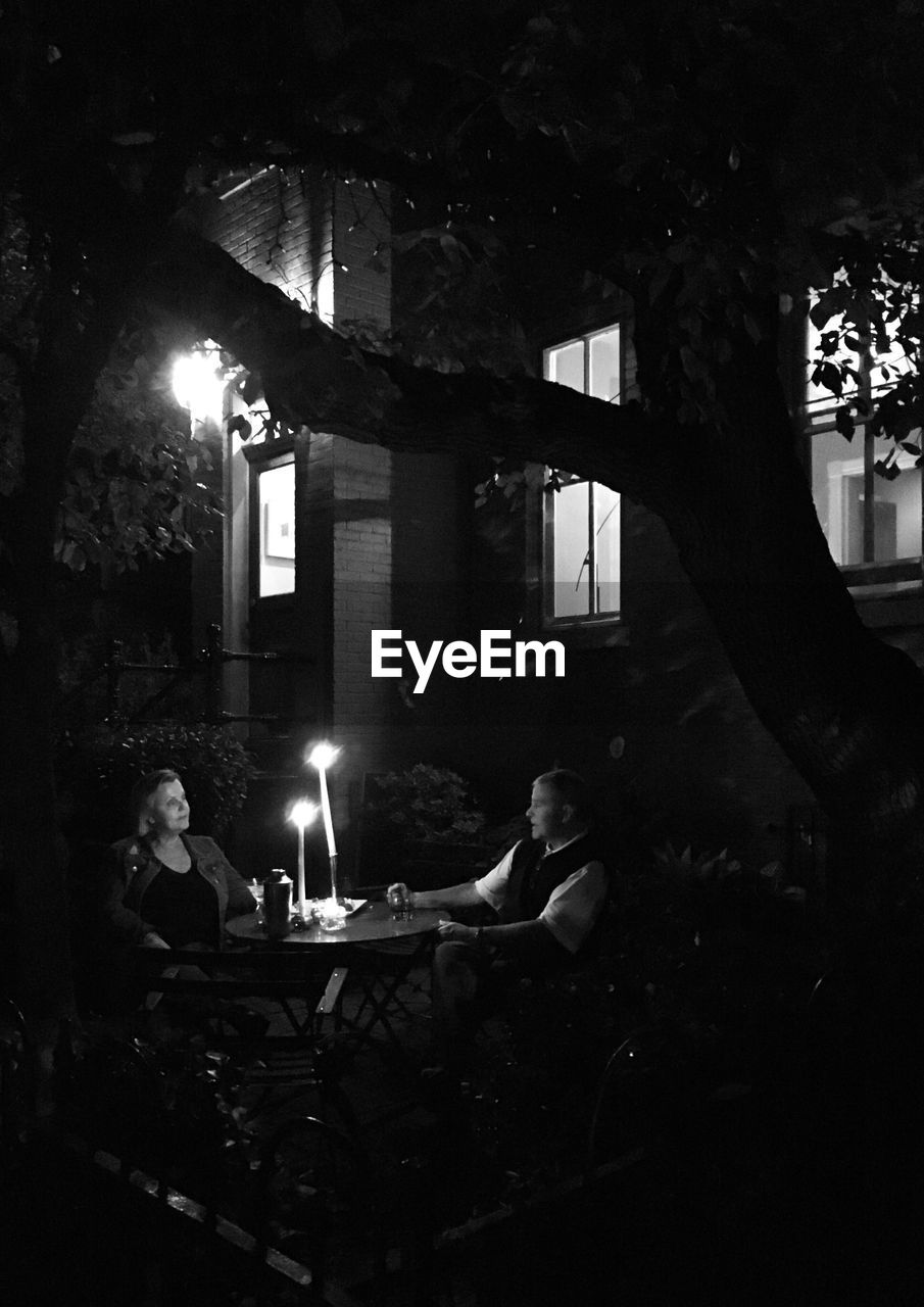 PEOPLE SITTING IN ILLUMINATED BUILDING