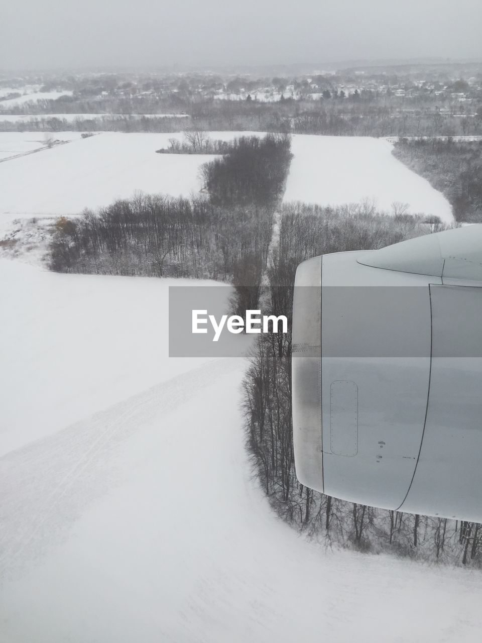 Cropped image of jet engine flying over snow covered landscape