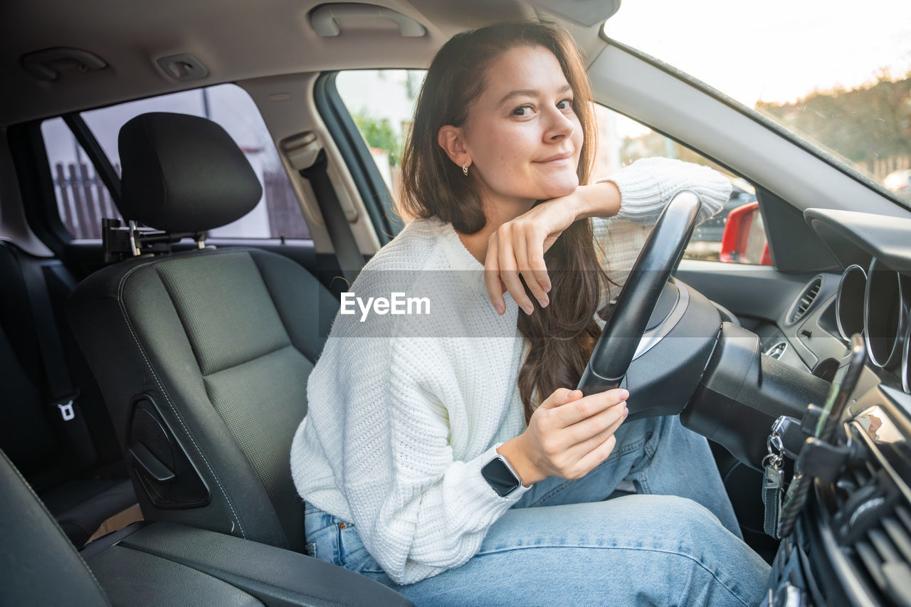 portrait of young woman using mobile phone while in car