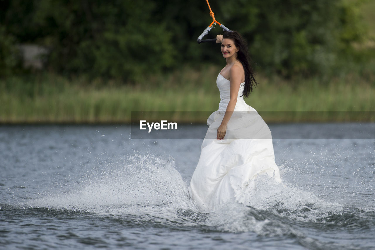 Side view portrait of bride kiteboarding in lake