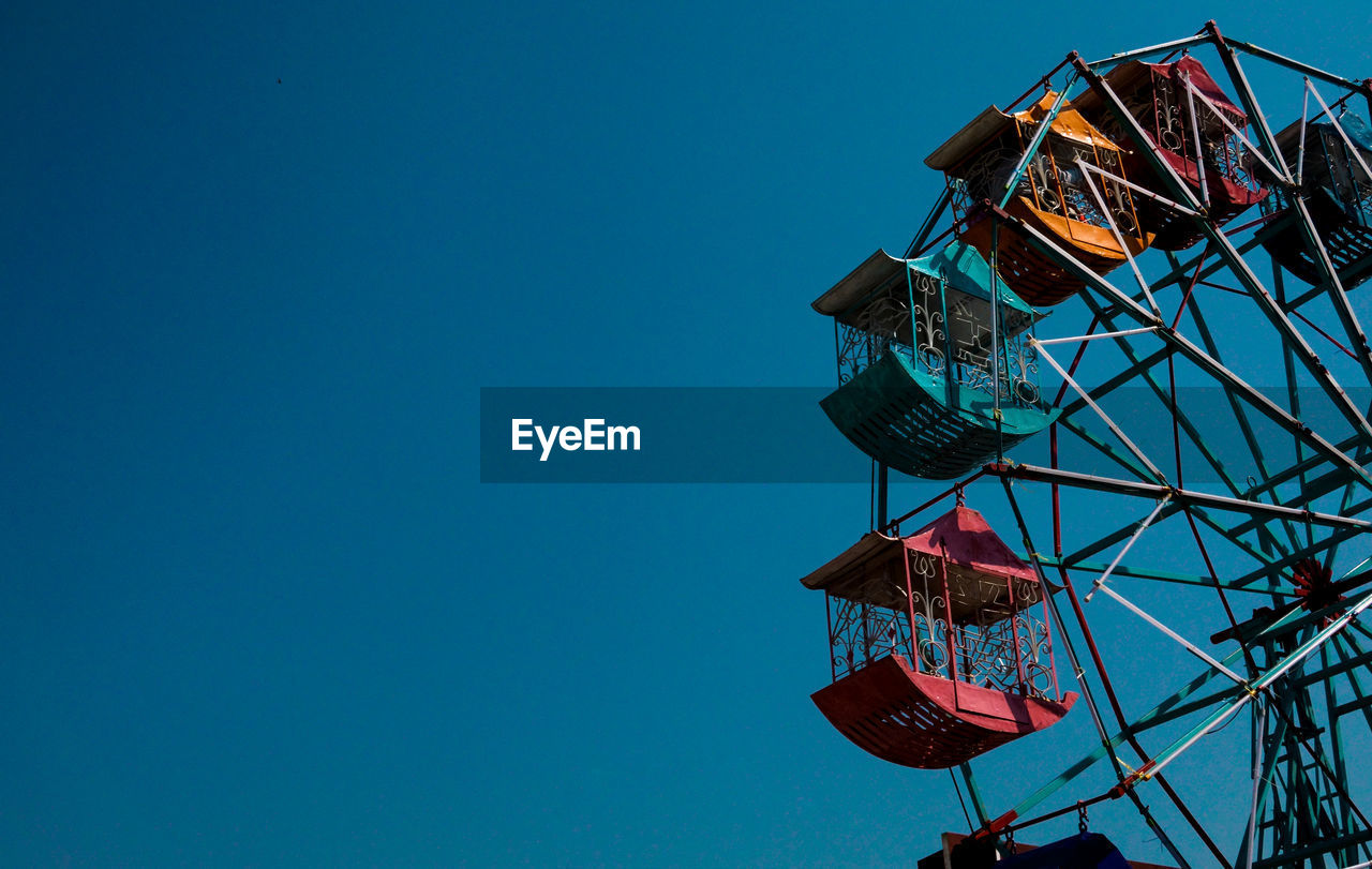 Low angle view of ferris wheel against blue sky