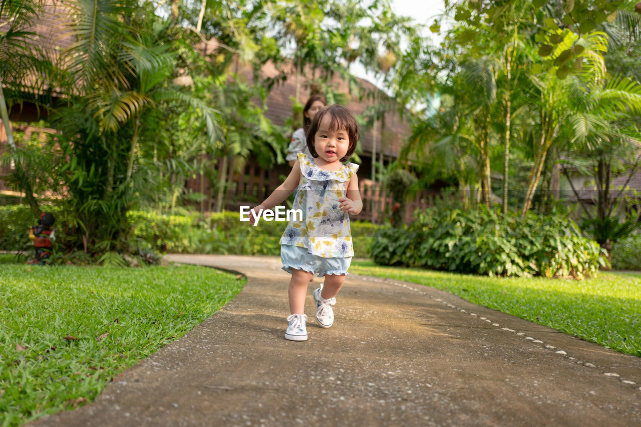 Portrait of cute girl walking on footpath in park