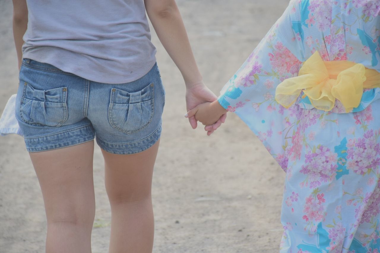 Rear view of siblings holding hands while walking at beach