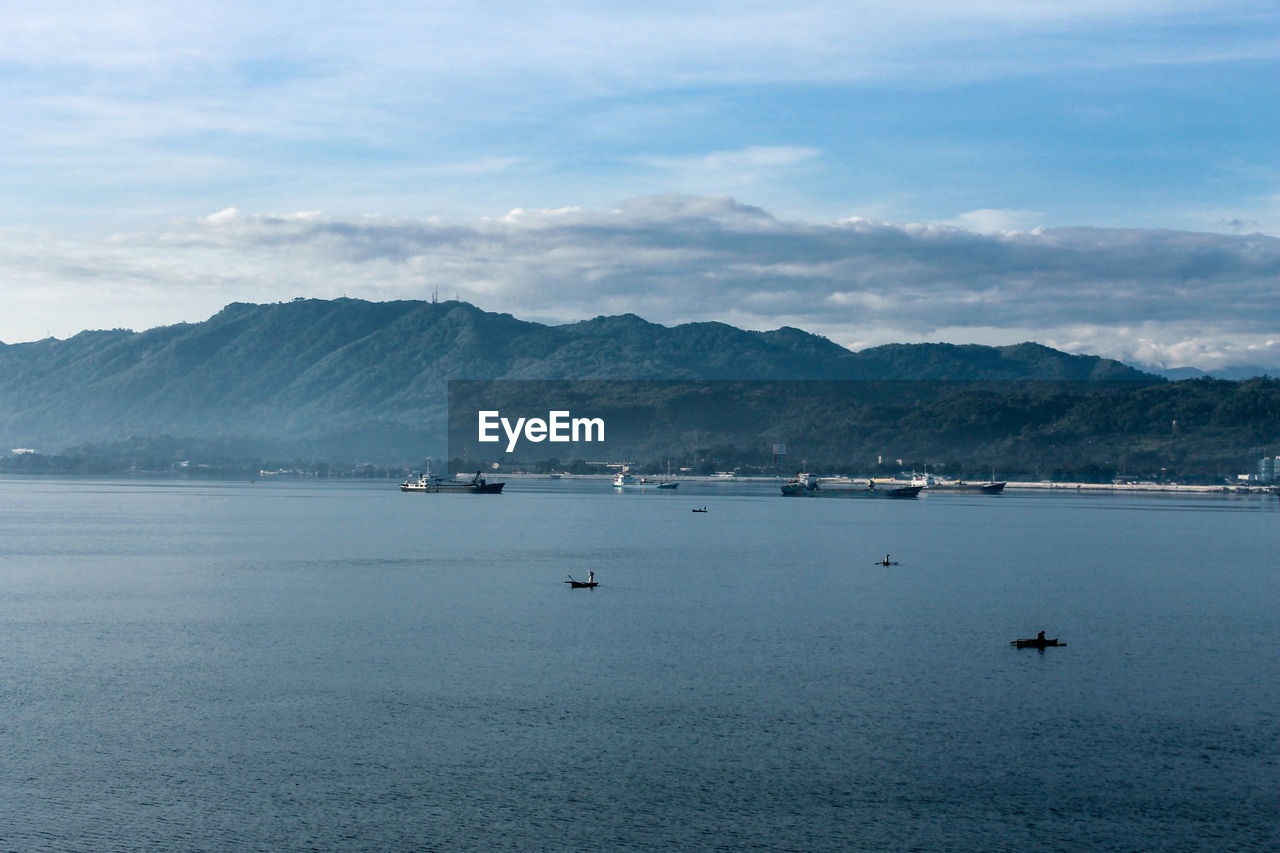 Scenic view of sea by mountains against sky