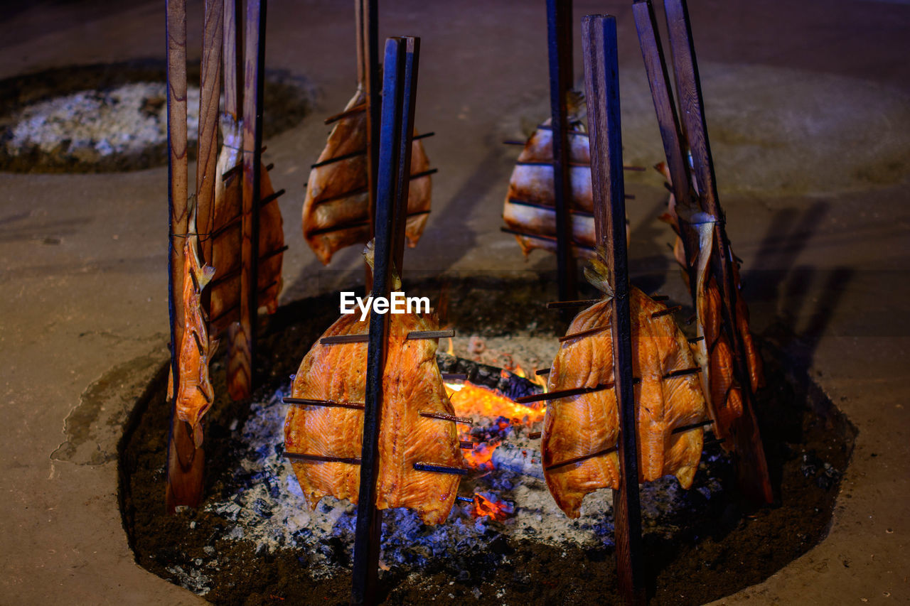 Close-up of salmon tied to stick at bonfire