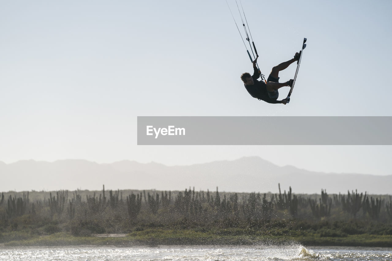 Professional male athlete kiteboarding on a sunny day in mexico