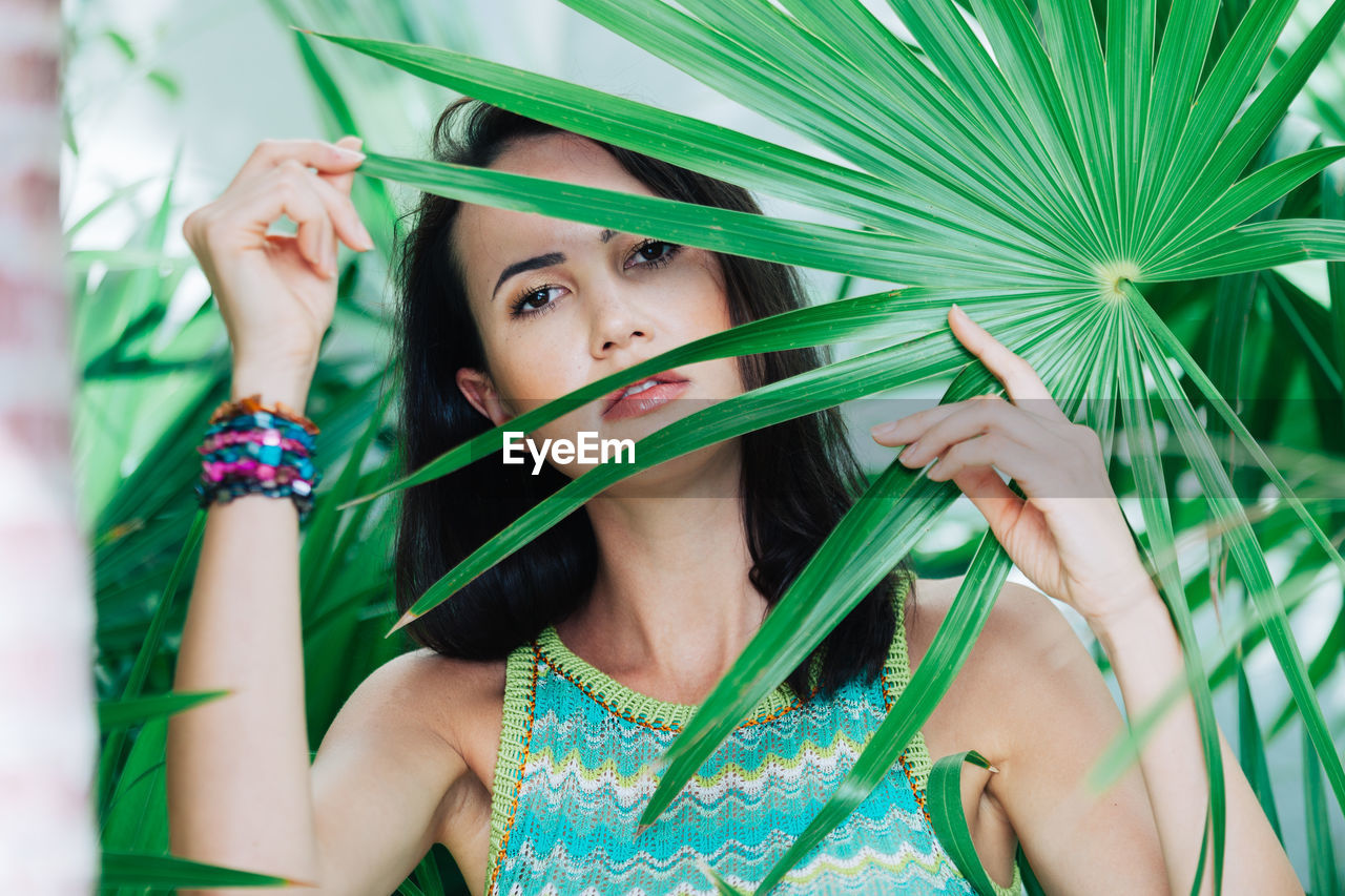 Portrait of young woman holding plant