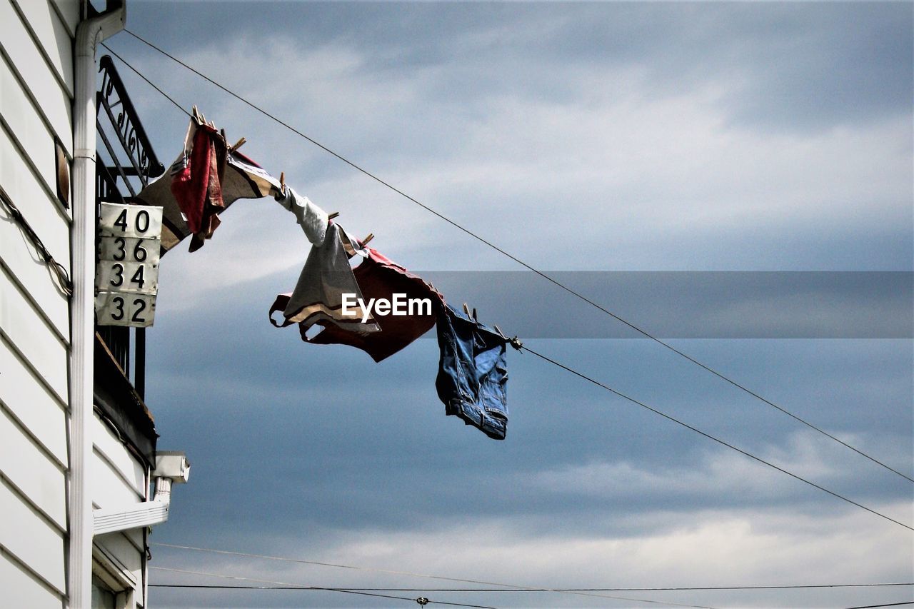 Low angle view of laundry hanging on clothesline against cloudy sky