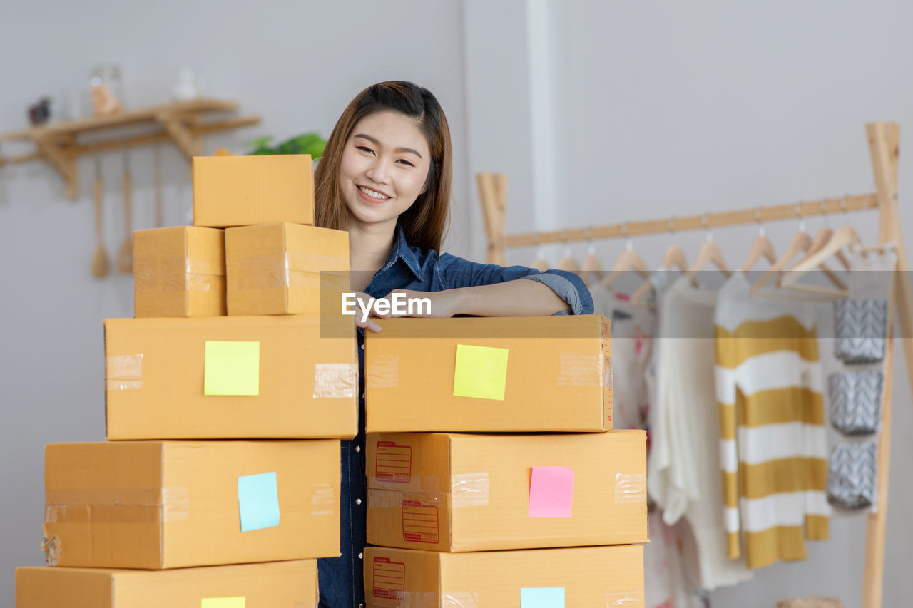 Portrait of smiling woman holding boxes