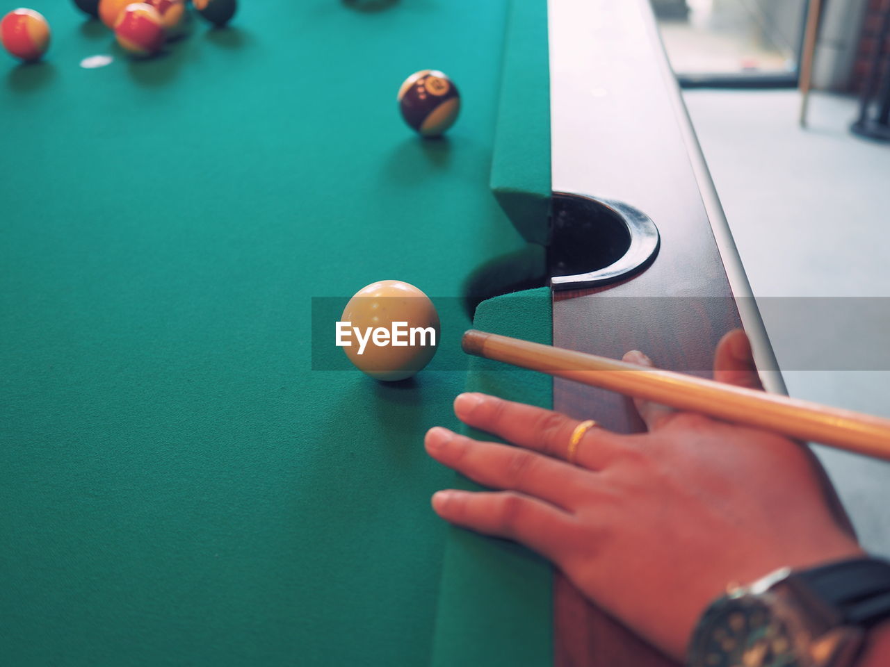 CLOSE-UP OF MAN PLAYING WITH BALL IN POOL