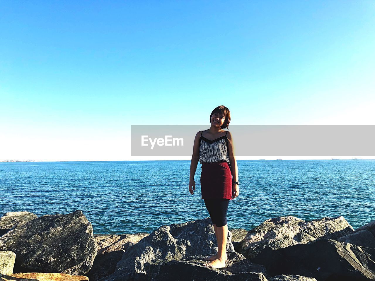 FULL LENGTH OF MAN STANDING ON ROCK AGAINST SEA