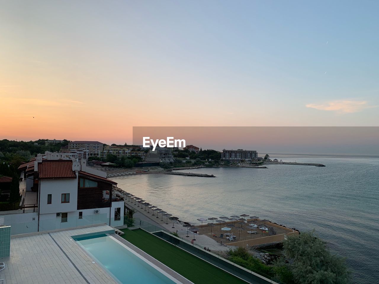 HIGH ANGLE VIEW OF CITY BY SEA AGAINST SKY