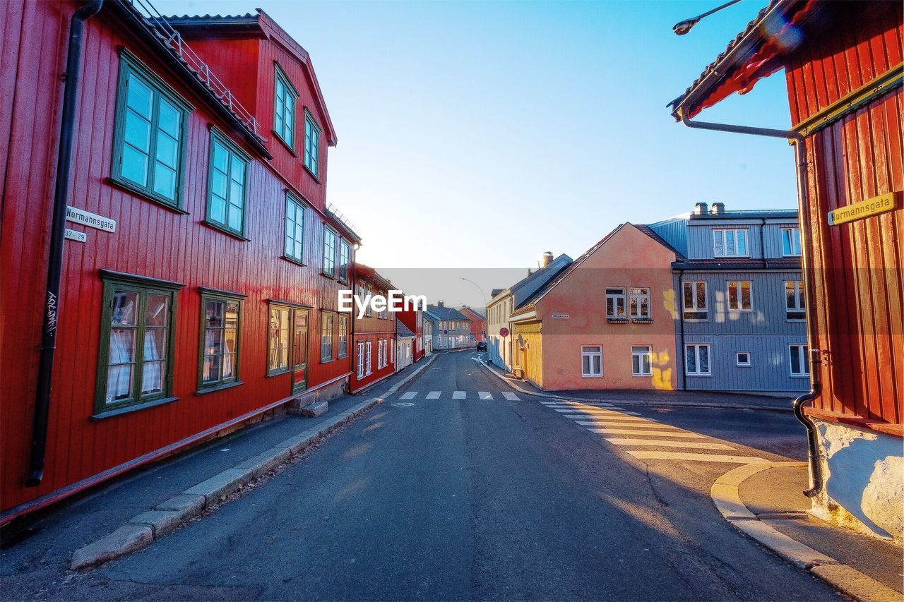 Road amidst buildings against clear sky