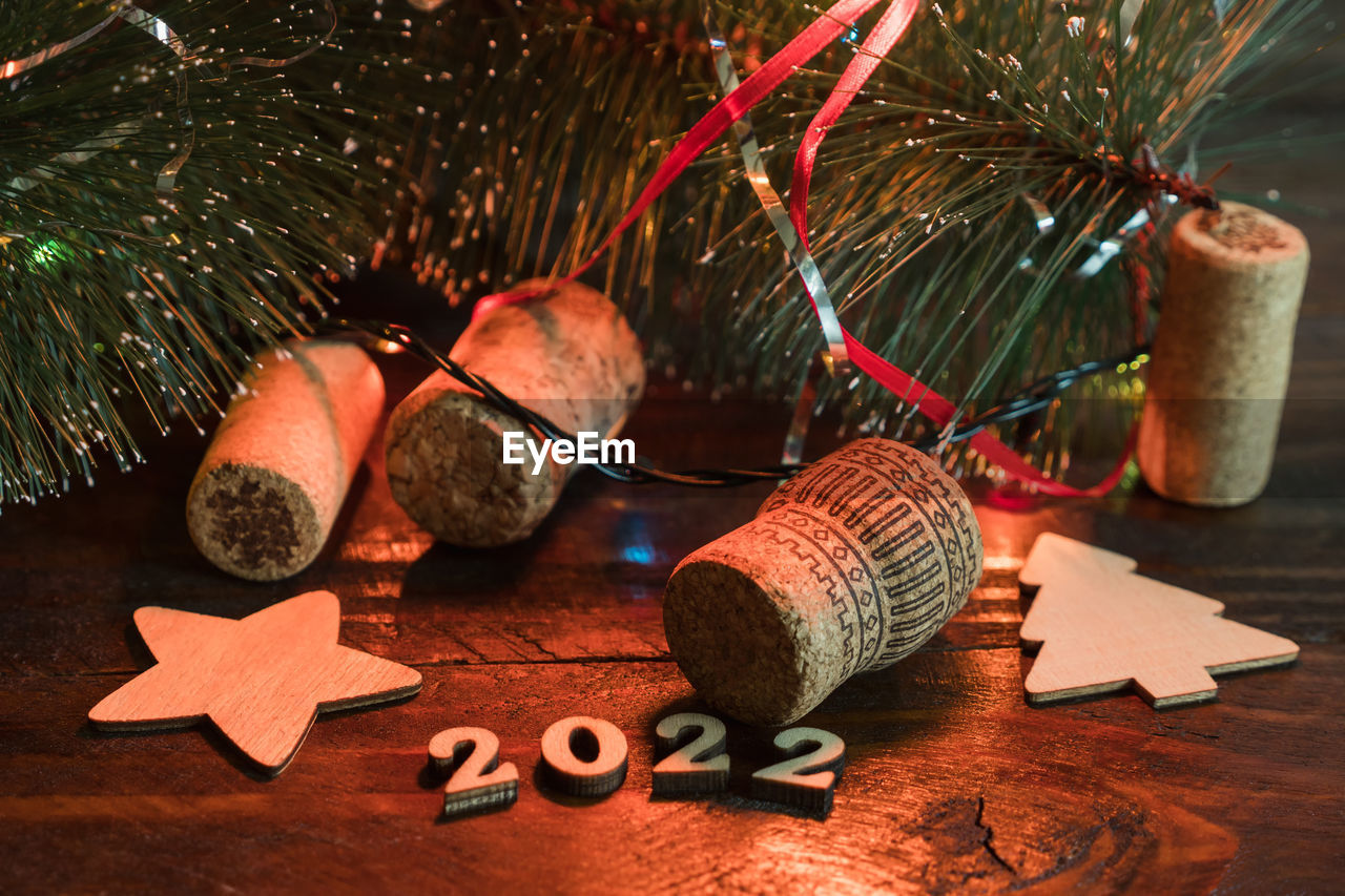 New year 2022 symbols laying on the dark wooden board, christmas tree, wine.