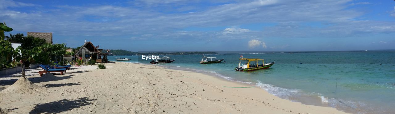 BOATS MOORED ON BEACH AGAINST SKY