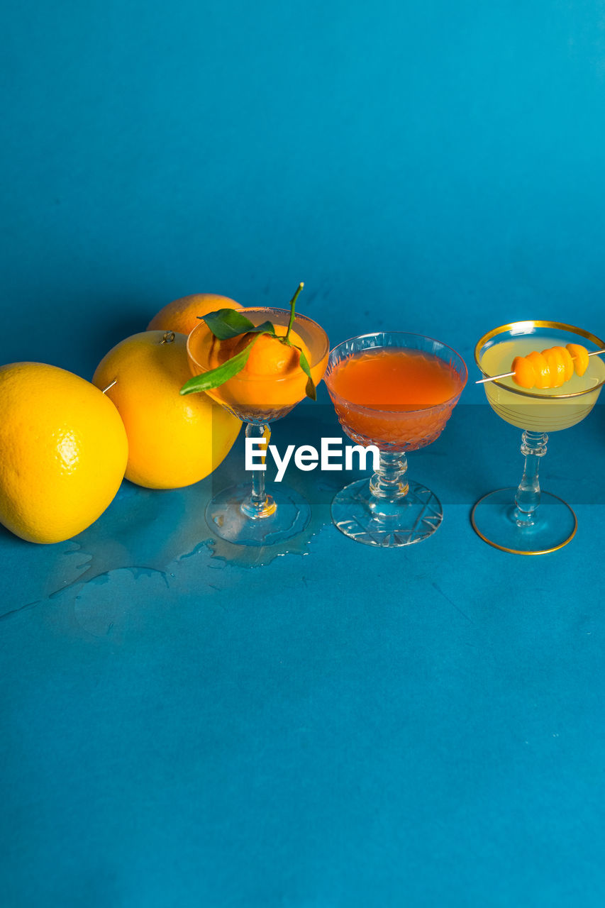 Messy citrus cocktails orange grapefruit lemon on teal blue background