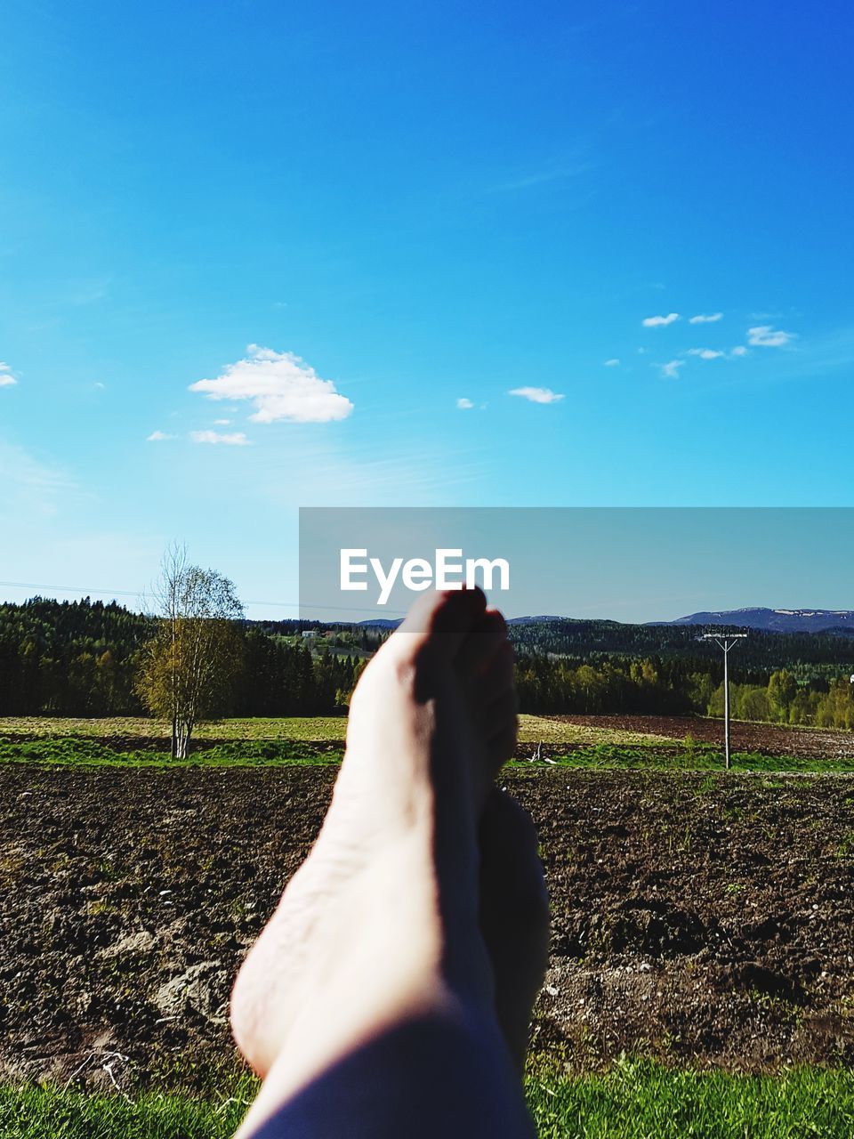 LOW SECTION OF MAN STANDING ON FIELD AGAINST SKY