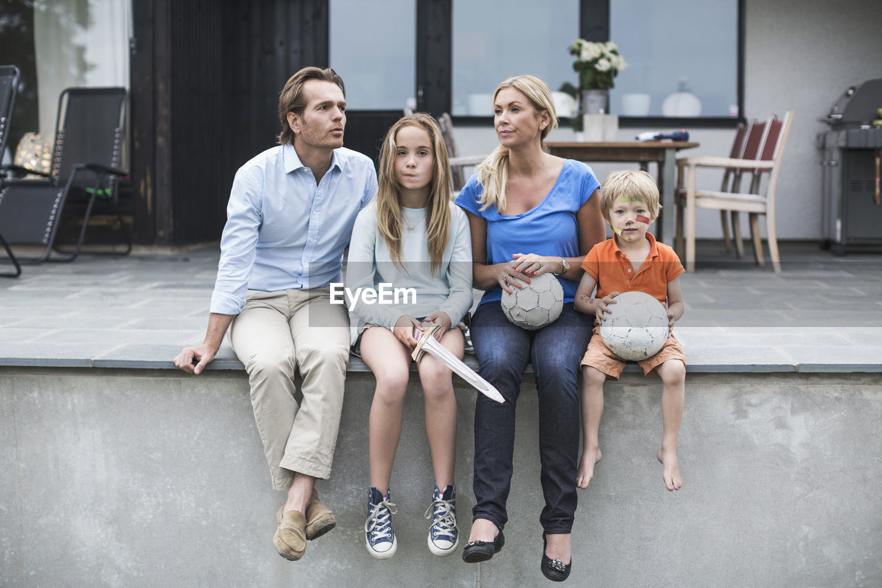 Family with footballs sitting at porch