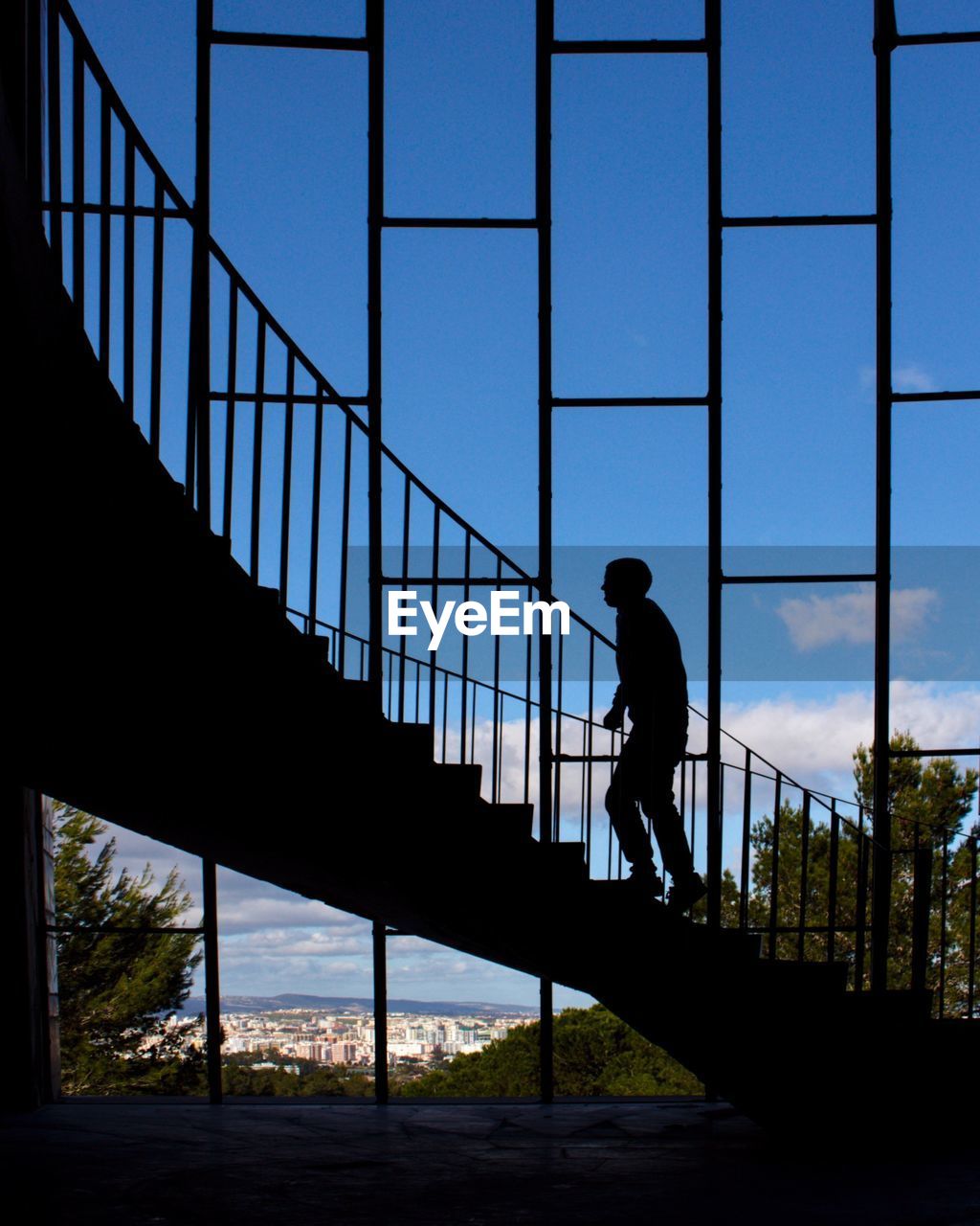 Silhouette man walking on staircase against sky