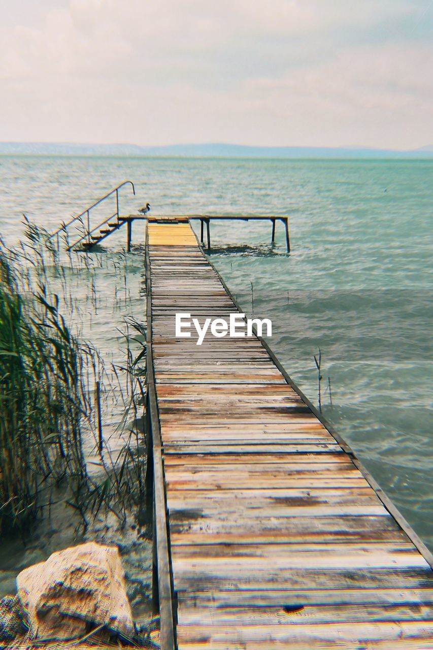 Wooden pier on sea against sky