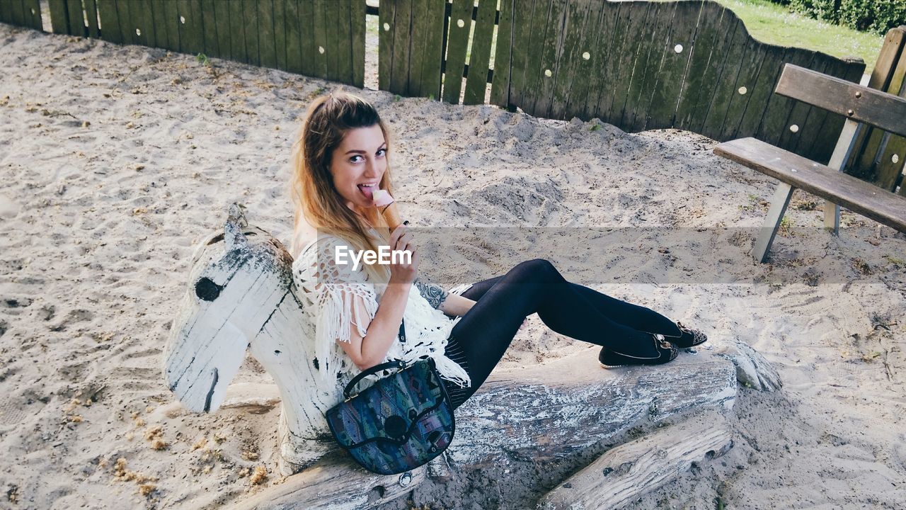 Portrait of young woman smiling and eating ice cream on beach