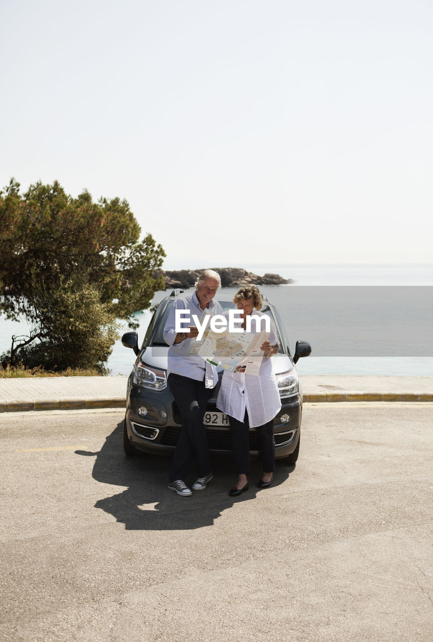Couple standing in front of car looking at next destination for travel in map