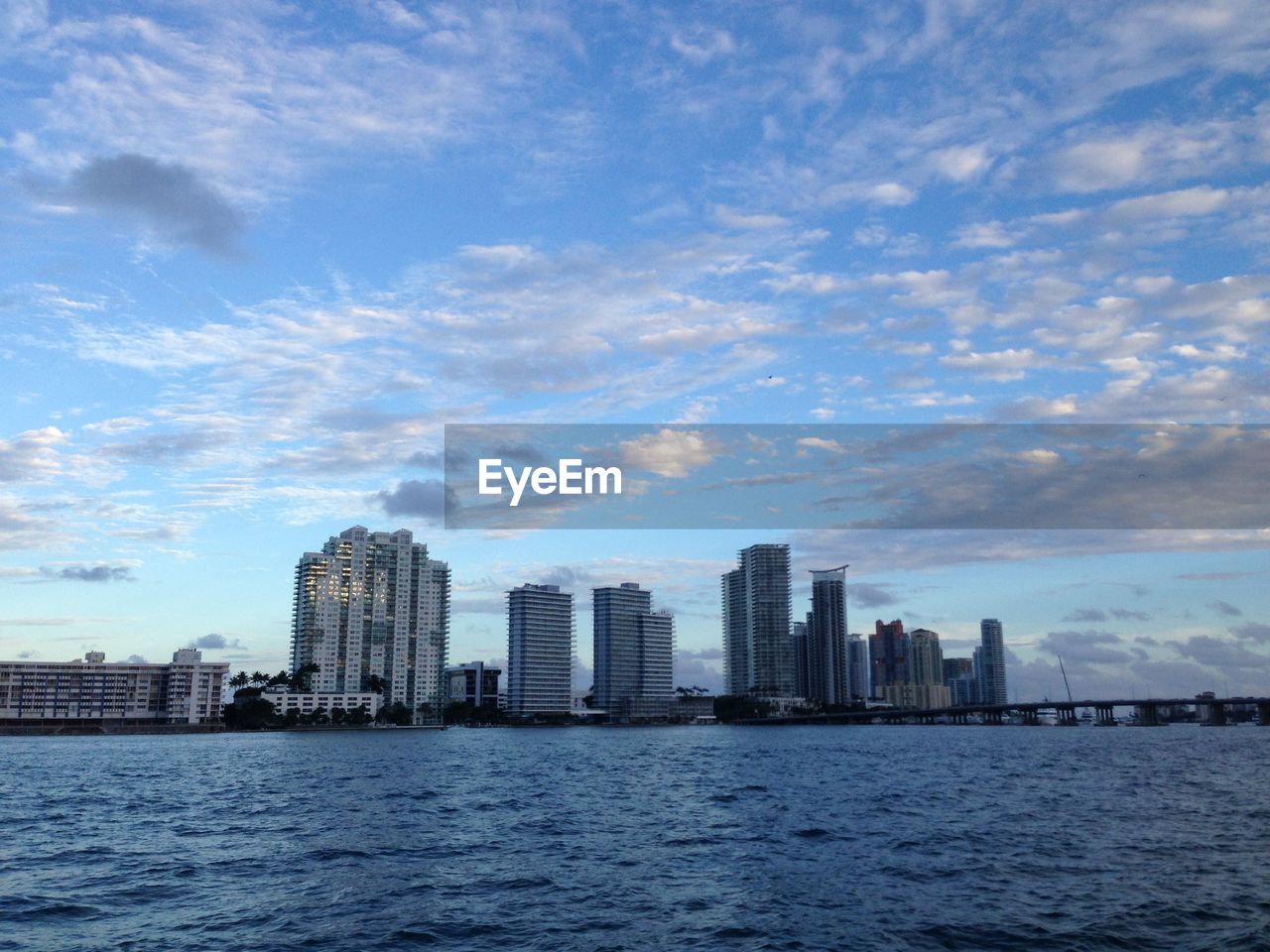 Sea by buildings in city against sky