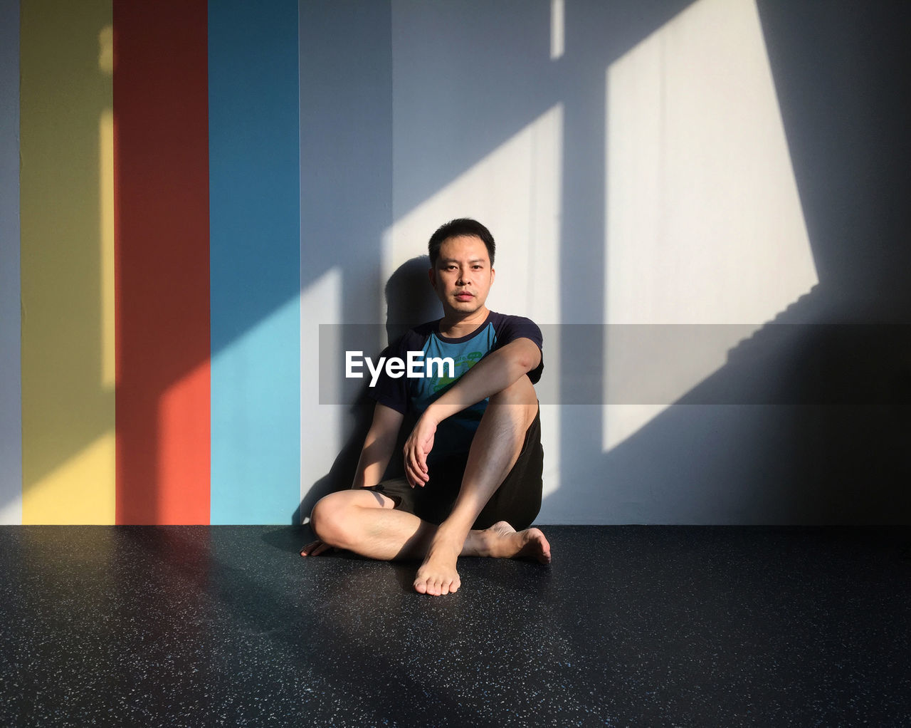 Portrait of man sitting against wall