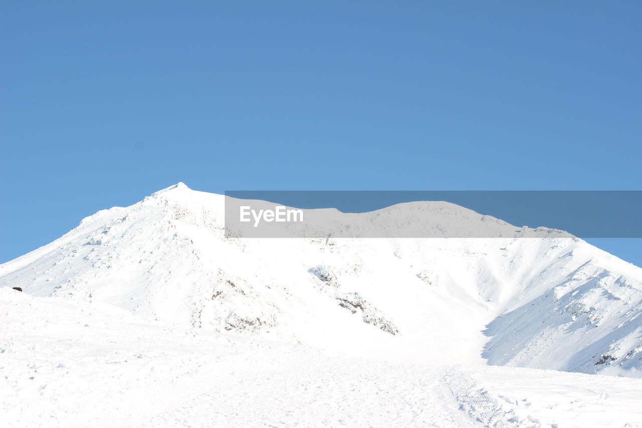 Scenic view of snowcapped mountains against clear blue sky