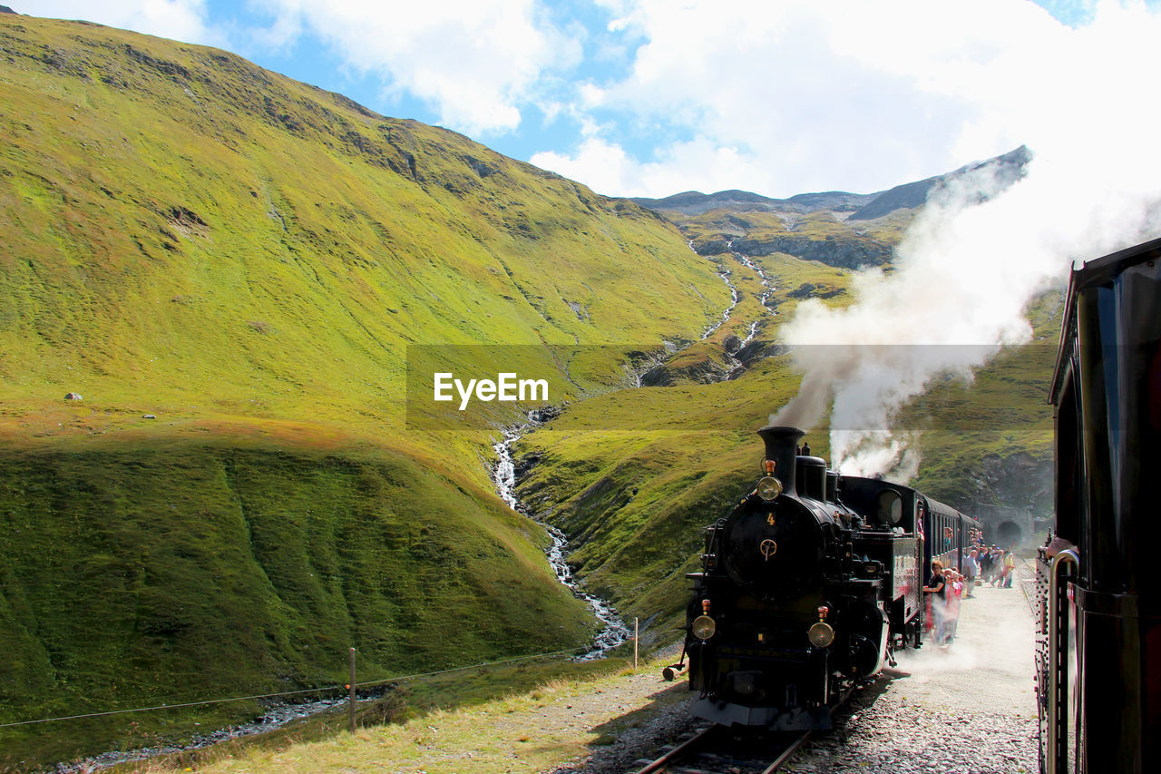 SCENIC VIEW OF TRAIN AMIDST MOUNTAINS AGAINST SKY