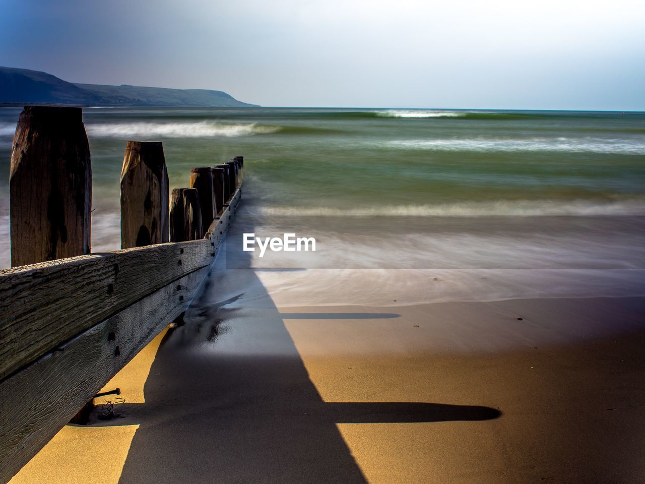 Wooden posts on beach against sky