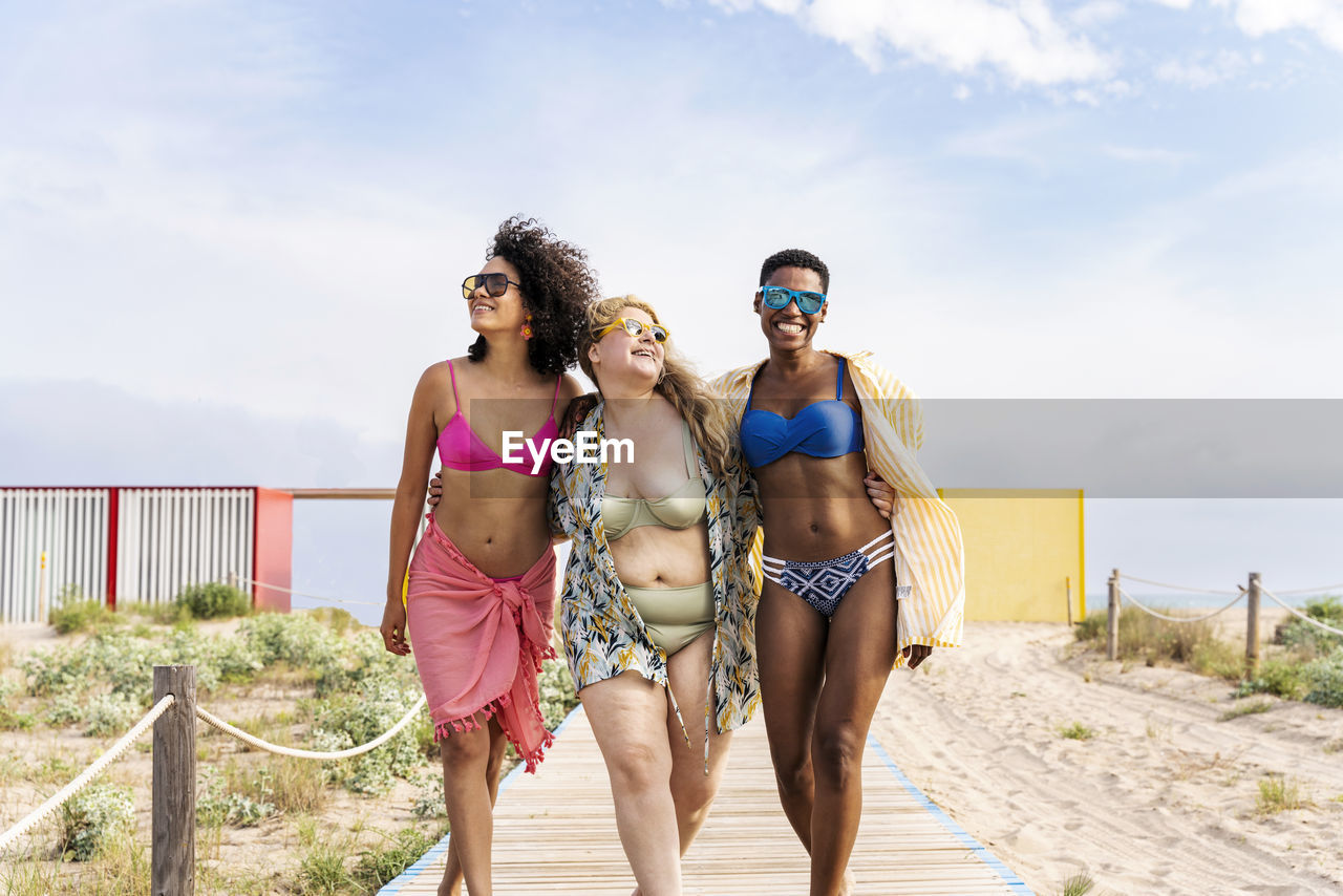 Carefree multiracial friends walking at beach