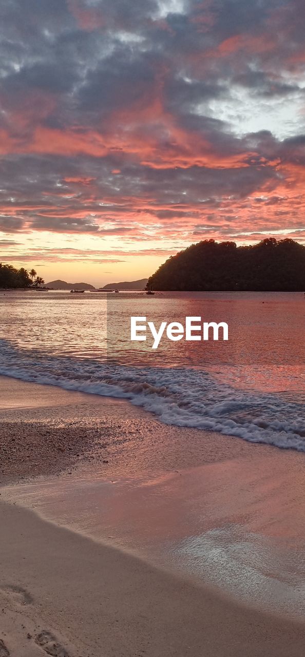 Scenic view of sea against dramatic sky during sunset