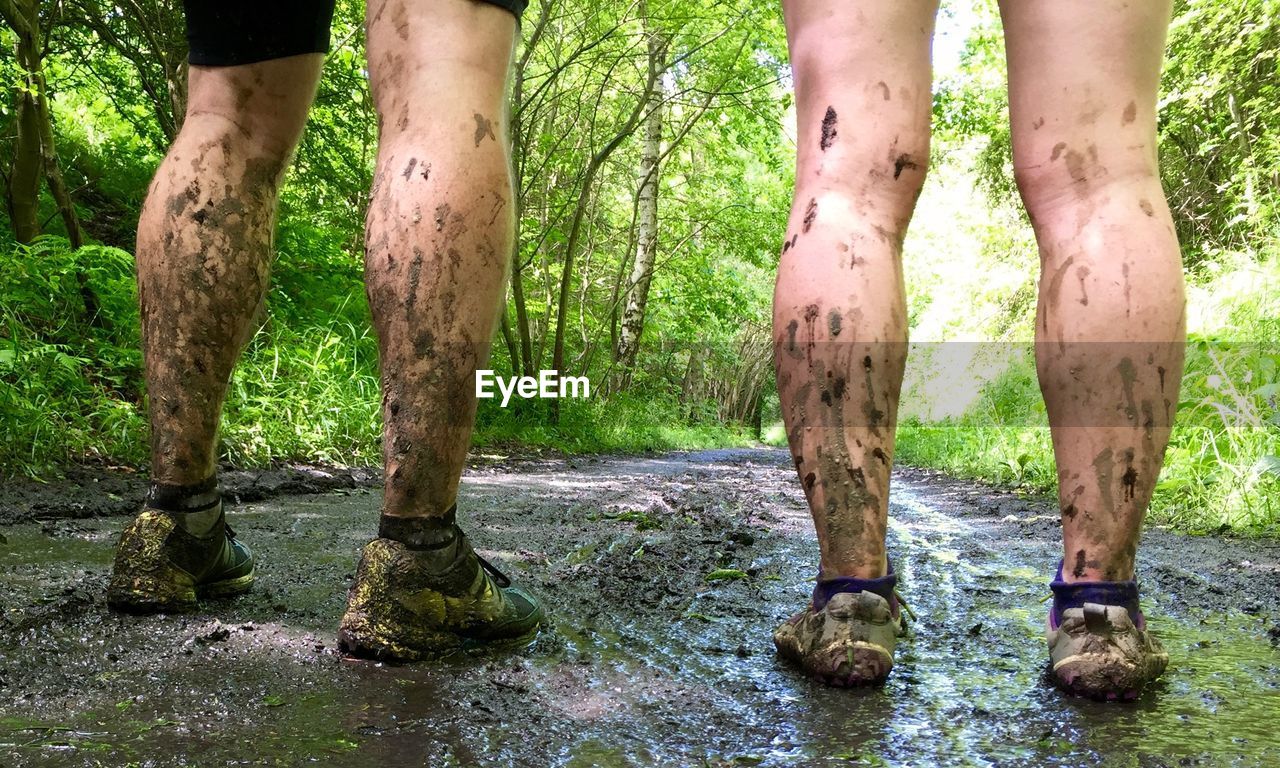Low section view of couple with dirty legs in forest