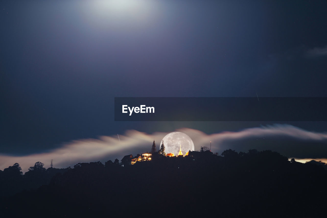 Silhouetted skyline against full moon