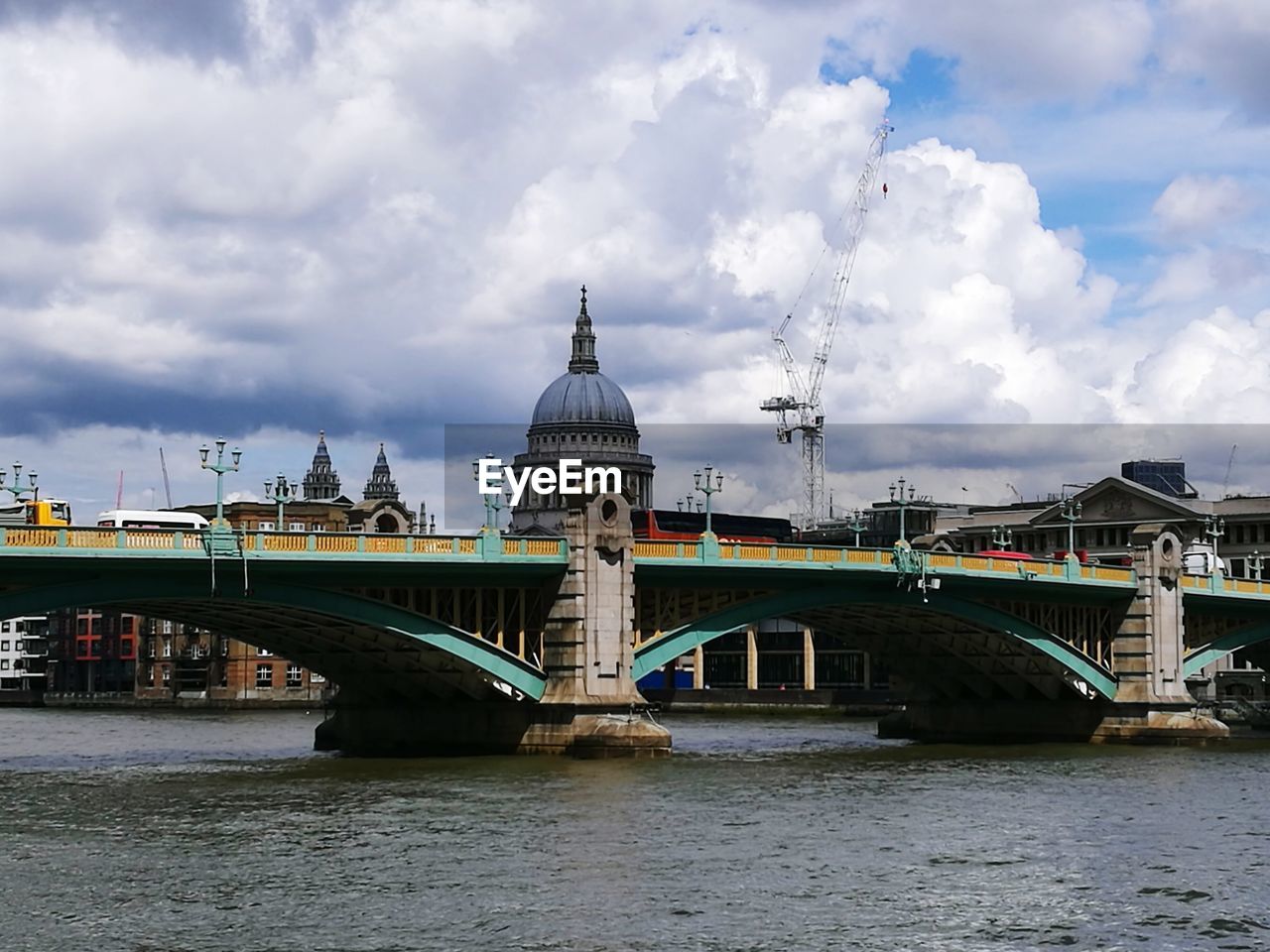 Bridge of old town over river against cloudy sky