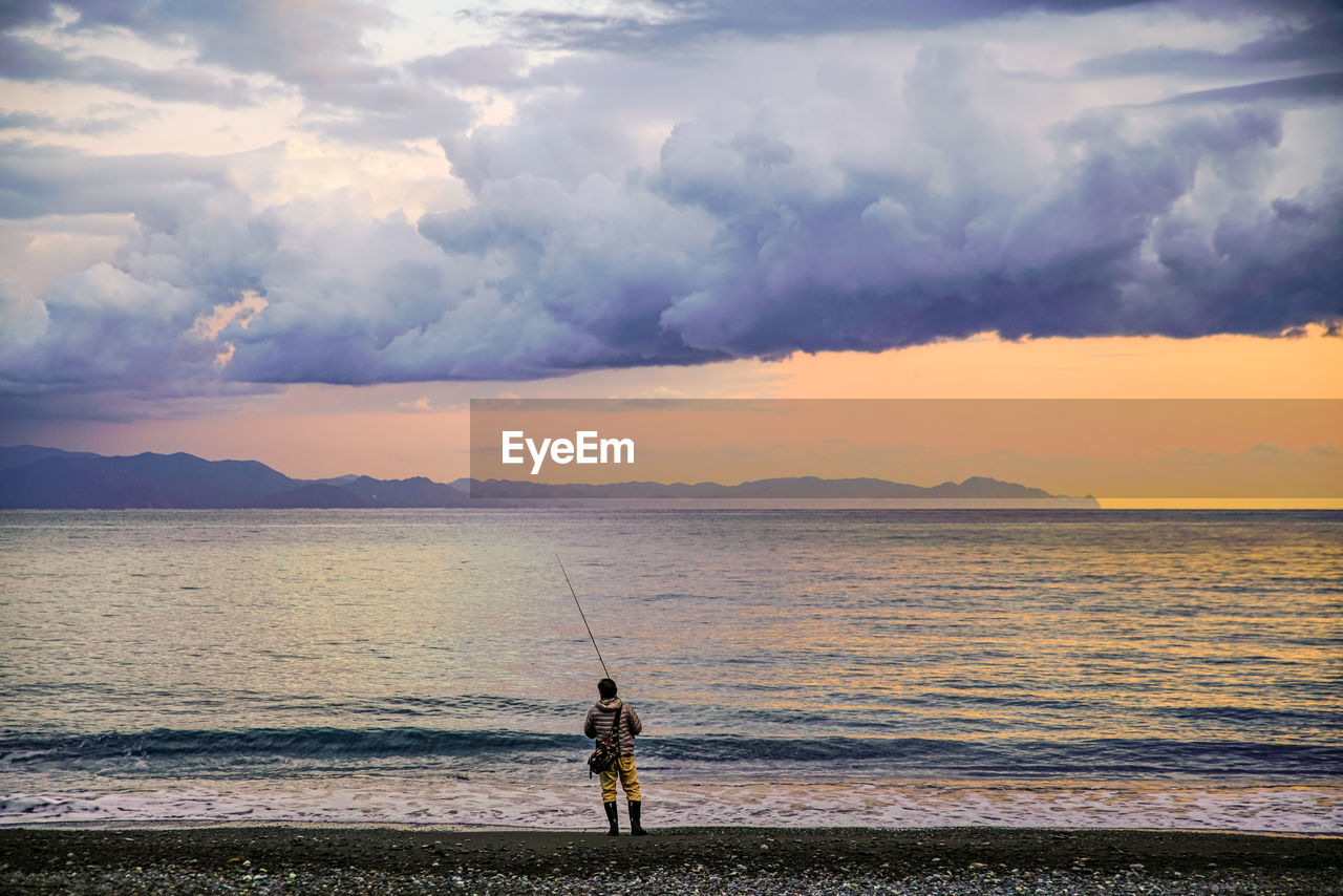 MEN FISHING IN SEA DURING SUNSET