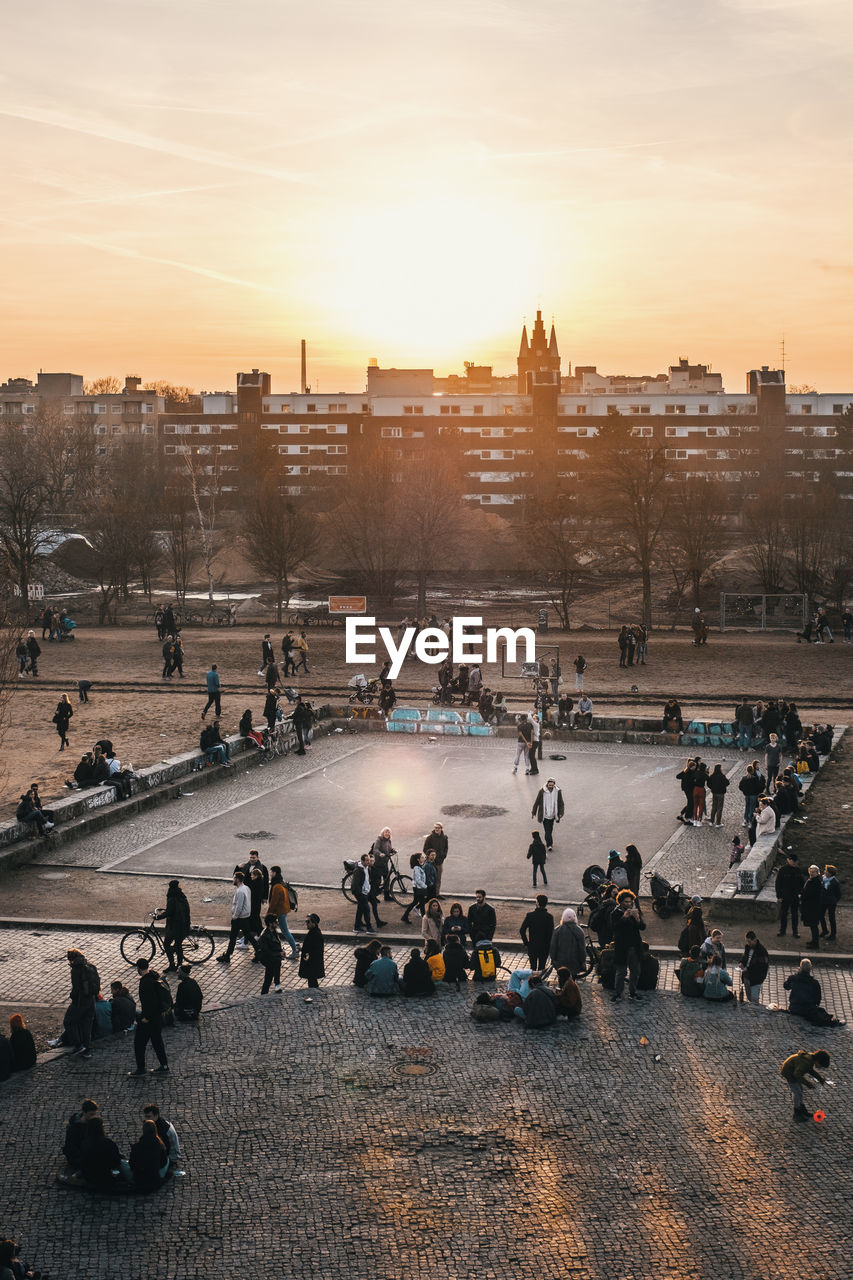 HIGH ANGLE VIEW OF PEOPLE ON STREET DURING SUNSET