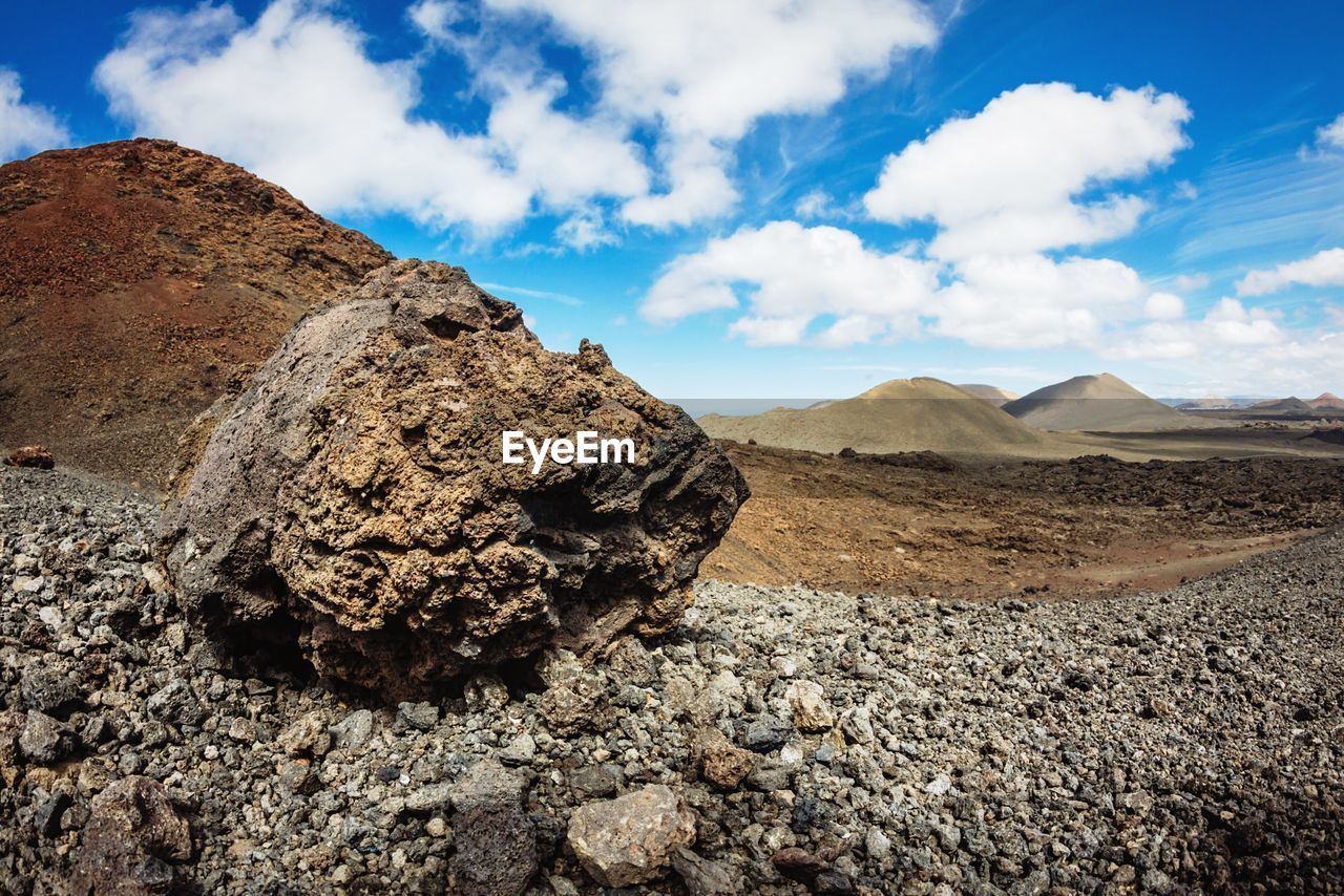 Rock on field by mountain against sky