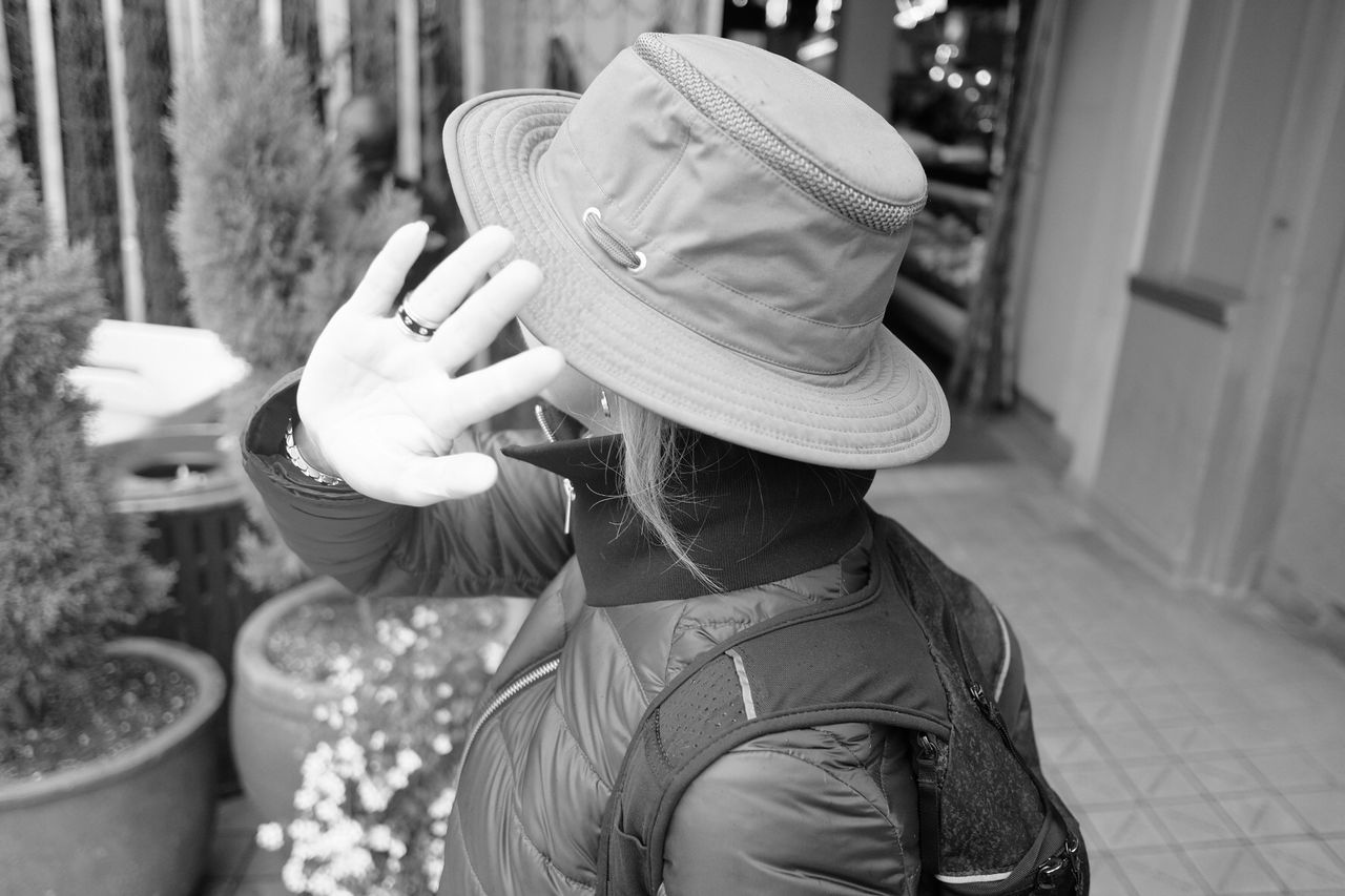 Woman wearing hat showing stop gesture while standing outdoors