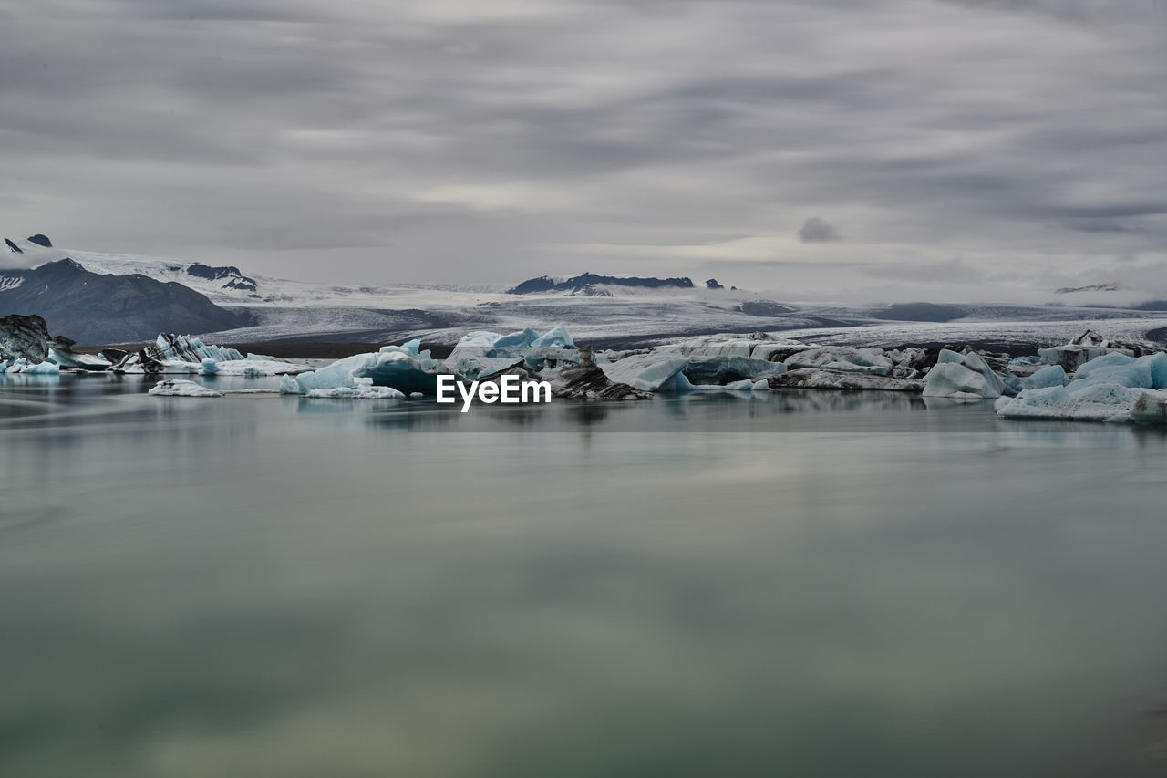 Frozen lake against cloudy sky