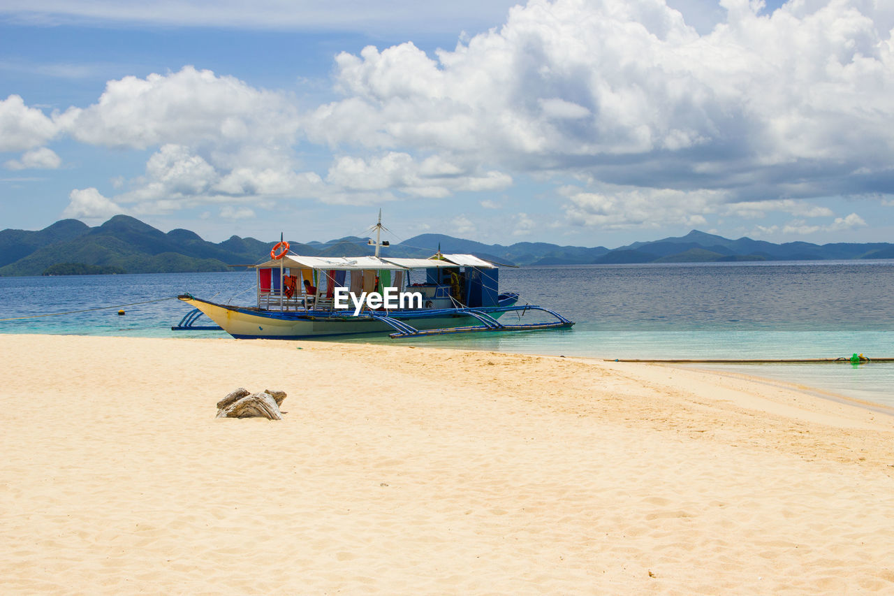 BOAT MOORED ON SHORE AGAINST SKY