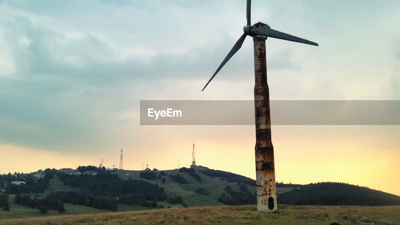 Windmill on field against sky during sunset